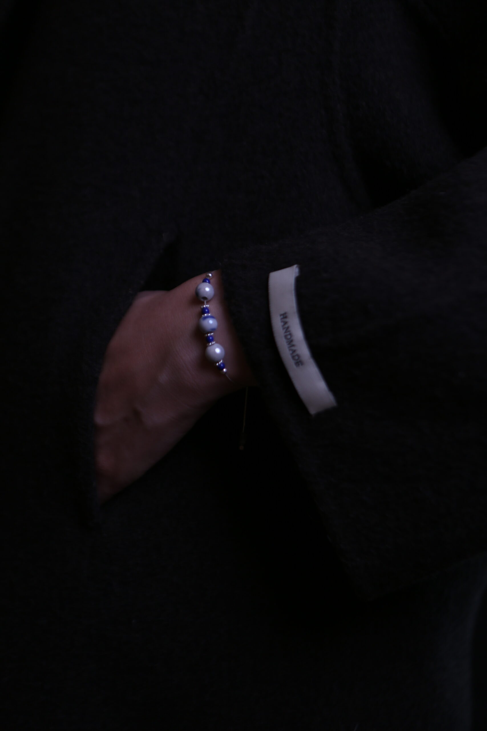 Blue porcelain preview bracelet worn with dark textured sleeve