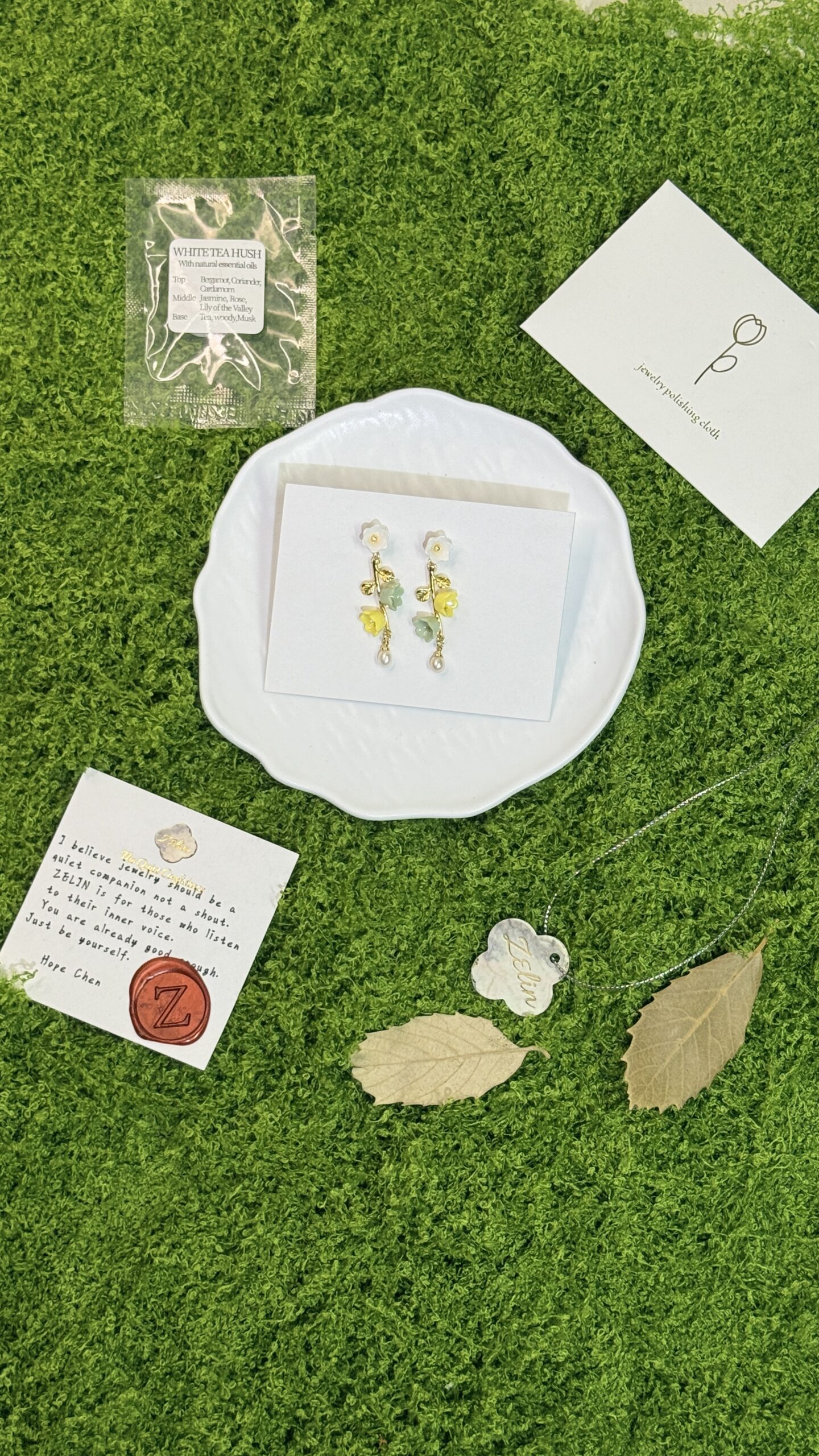 ZELIN ART packaging contents arranged with jewelry, card, scent sachet and porcelain tag